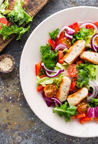 Healthy vegetable salad with grilled chicken breast, fresh lettuce, cherry tomatoes, red onion and pepper